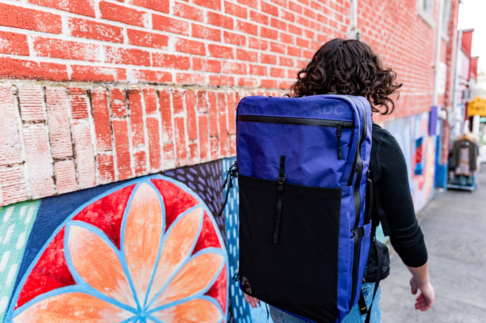 ADC travel backpack in cosmic berry color walking down the street