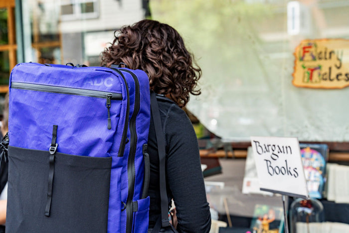 ADC travel backpack in cosmic berry color at a book stand