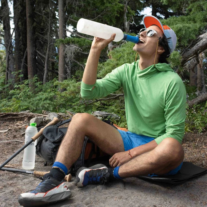 Thribottle being held up to the mouth with a water filter attached to the neck of the open bottle