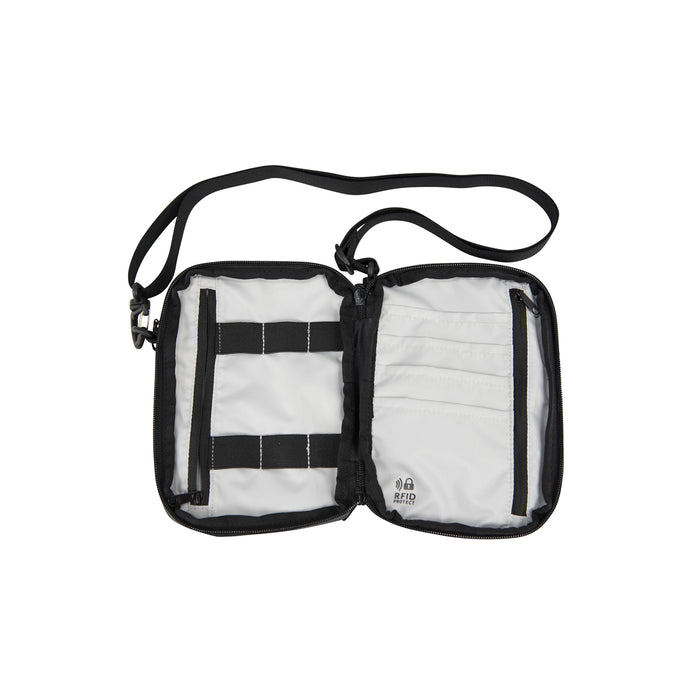 Black crossbody Passport Pouch open showing all of the pockets but they are all empty.  With a strap on a white background