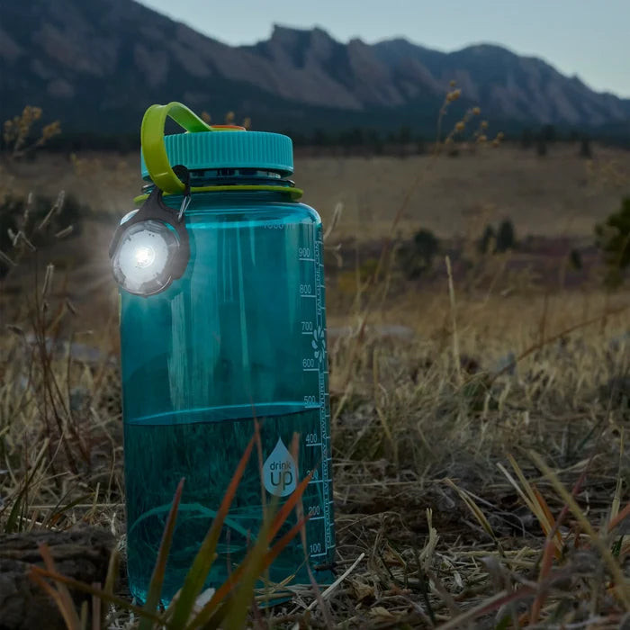 Nite Ize Moonlit Rechargeable Micro lantern clipped to a Nalgene bottle in the nature.